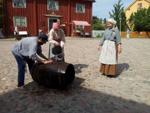Ein Mann und zwei Frauen waschen Kleidung am Kryddbodtorget im Freilichtmuseum Gamla Linköping.